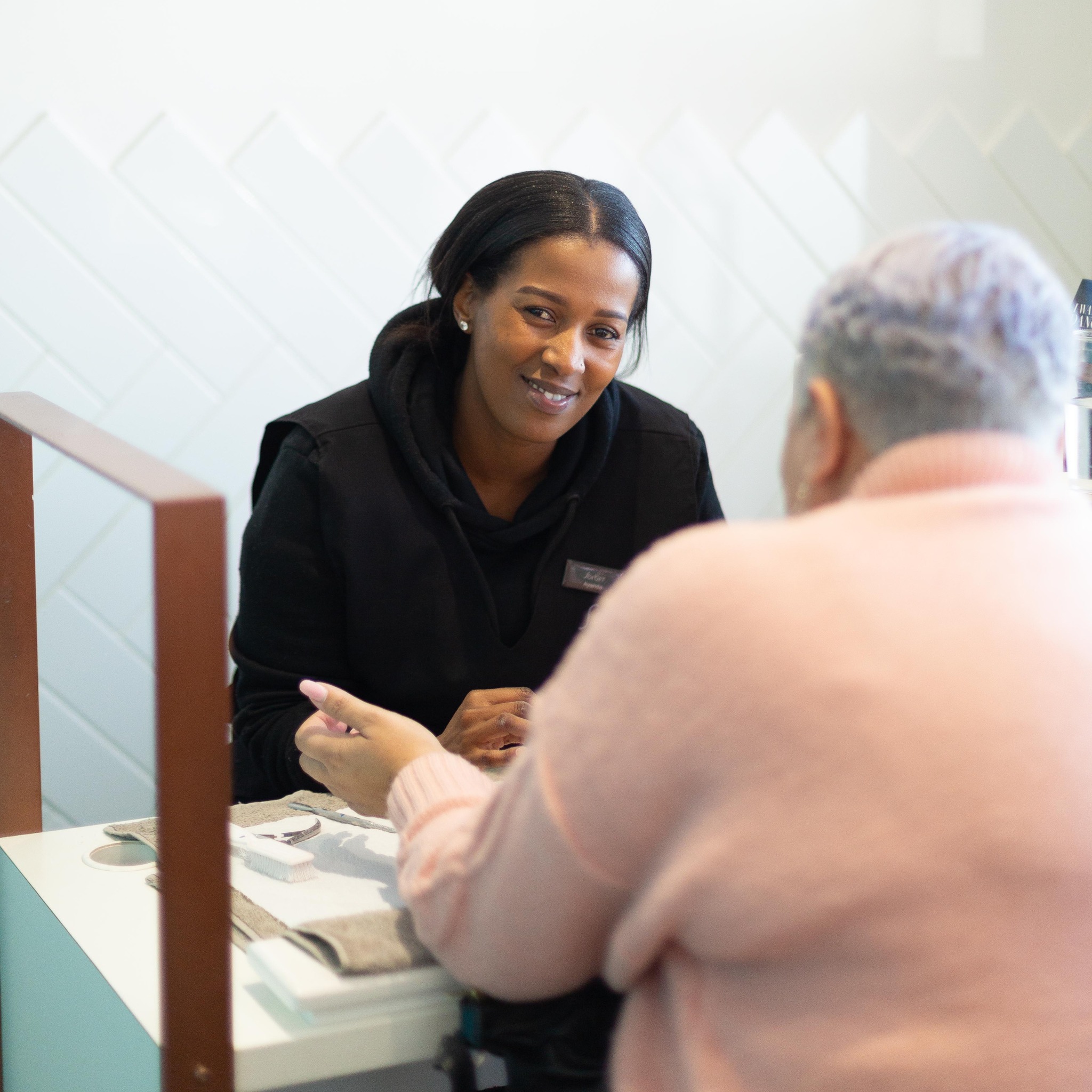 Smiling nail technician with a client