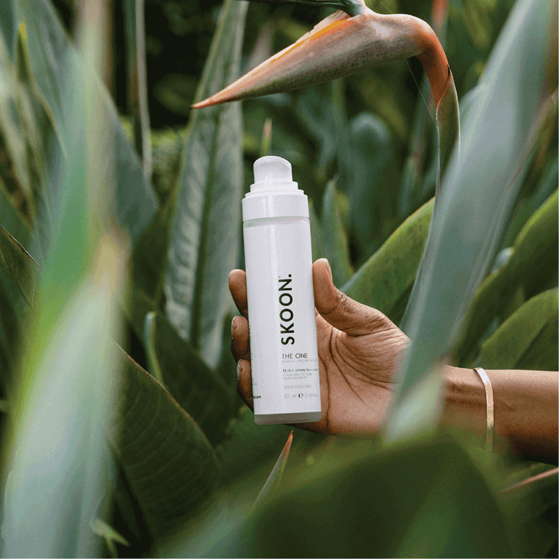 Hand holding a bottle of SKOON. The One beauty product, a natural and organic skincare item