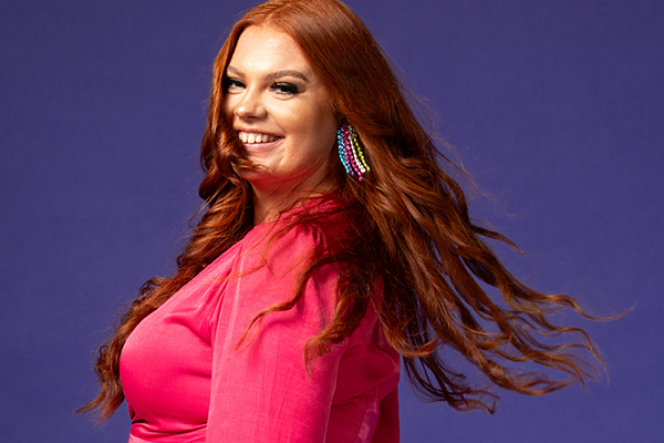 Lady with long flowing red hair and colorful earrings